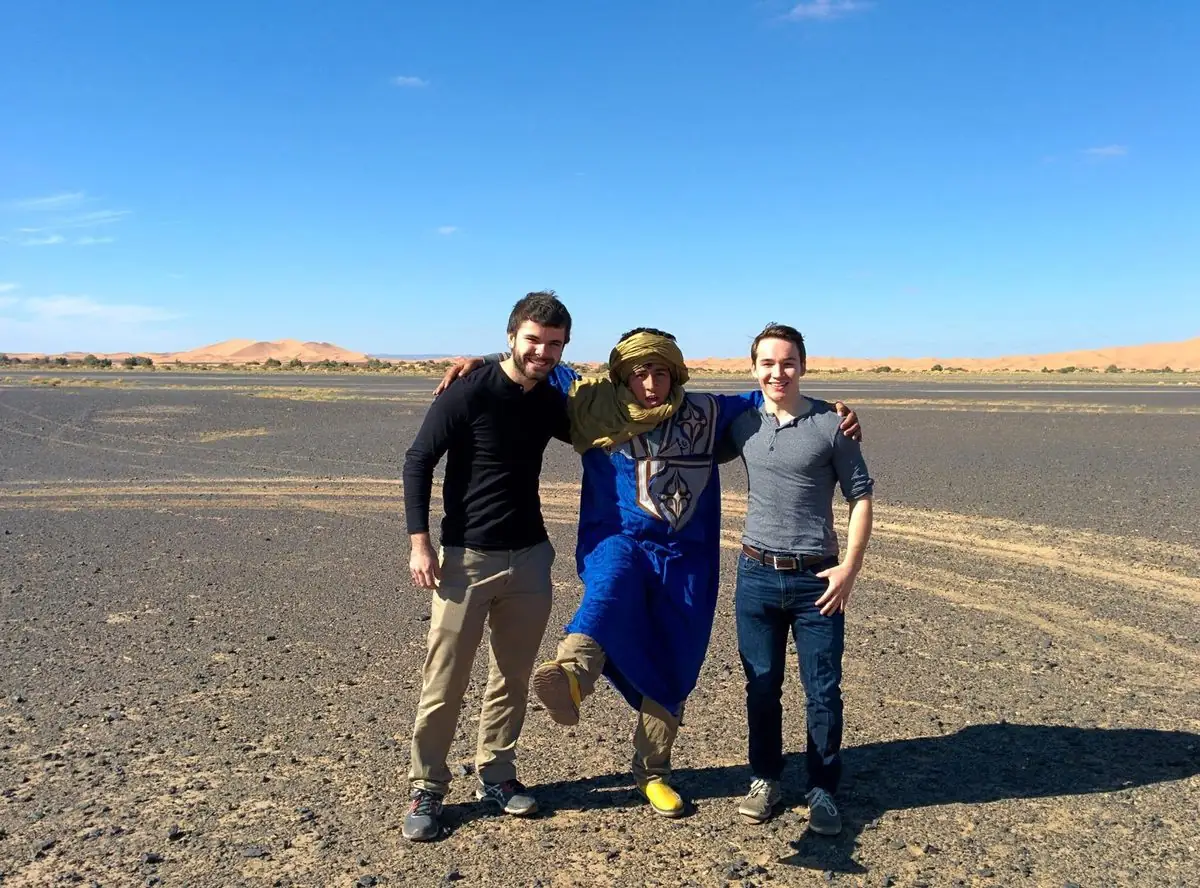 Una guida con due viaggiatori nell'hamada, con le dune sullo sfondo